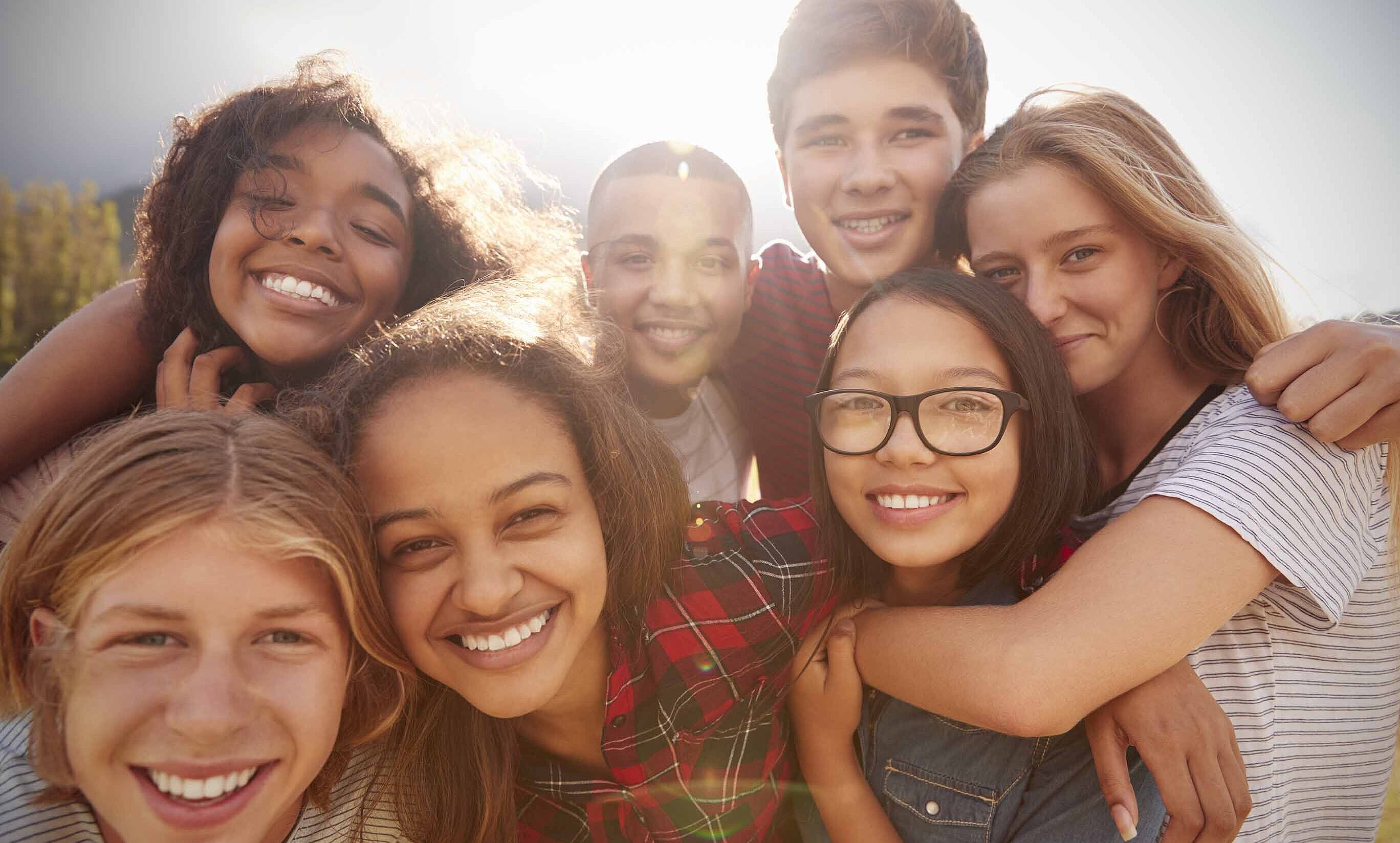 Teenage school friends smiling to camera, close up